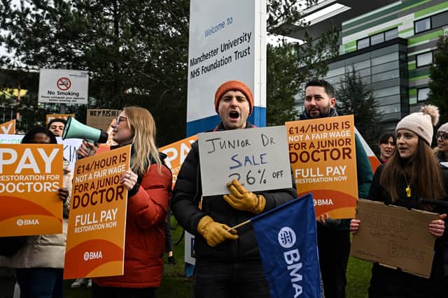 Demonstrators hold placards as they take part in a protest by junior doctors, amid a dispute with the government over pay, outside of Saint Mary's Hospital, in Manchester, on March 15, 2023.