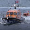 Dolphins swim alongside RNLI lifeboat in Whitby, North Yorkshire. 