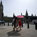 Pedestrians walk in the midday sun past the Palace of Westminster in central London on September 6, 2023 as the late summer heatwave continues.