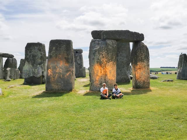 Activists sitting by Stonehenge after it was sprayed orange (Photo: Just Stop Oil / Supplied)