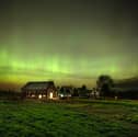 The northern lights fill the sky with green ribbons of electrical charged particles over a barn (Photo by Michael Seamans/Getty Images)