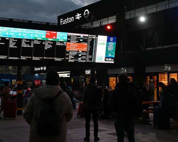 Rail travellers look at an electronic information board displaying train time information outside Euston Station in London. Photo: JUSTIN TALLIS/AFP via Getty Images