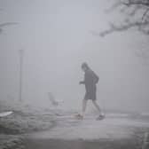 A jogger makes their way through fog on a frosty morning.