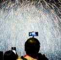 Person taking photo of a firework display. Photo: ANTHONY WALLACE/AFP via Getty Images