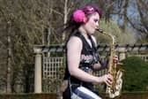 Rachel Ward unicycling while playing the saxophone