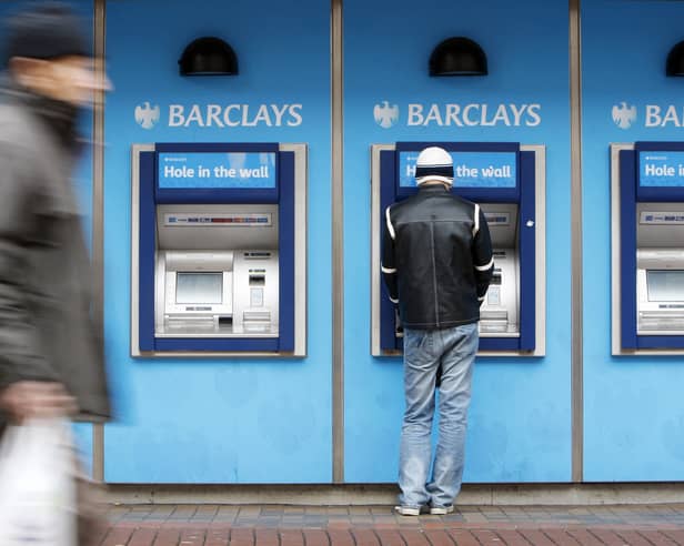 A man uses a cashpoint machine at a Barclays Bank 