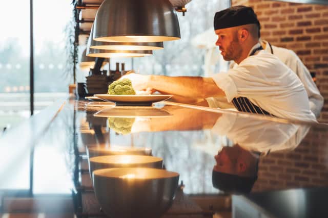 Chef putting final touches to dish in open kitchen