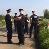 Five male police officers surround a female protester sat on the ground