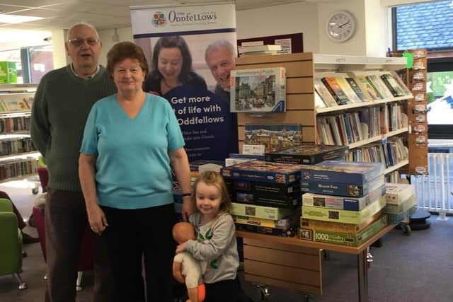 Jigsaw Swap volunteers David and Christine Saunders pictured with young volunteer Daisy O'Shea at Buckingham Library