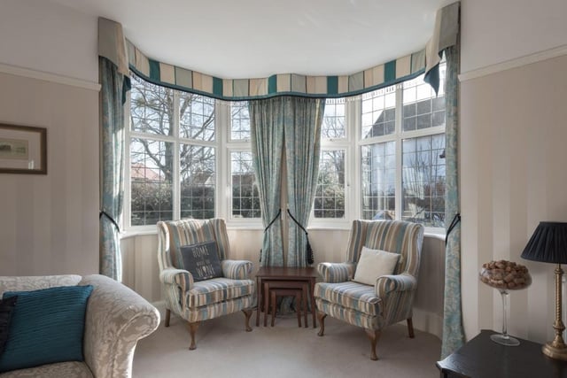 The sitting room boasts picture rails beneath a tall ceiling and an open fire