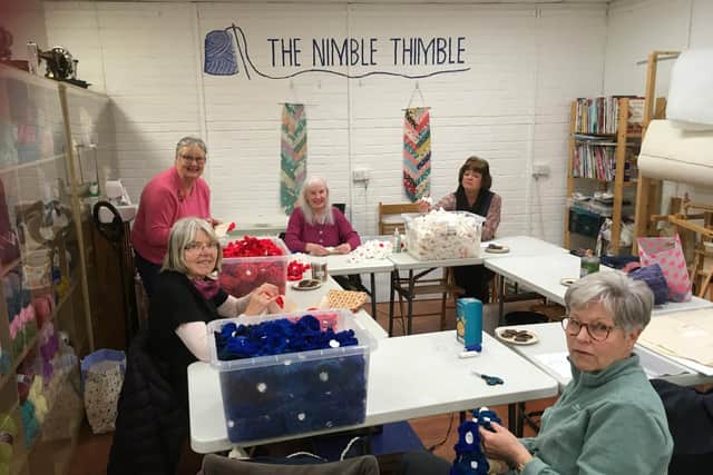 Stitchers at The Nimble Thimble sew knitted flowers on to a 10m banner