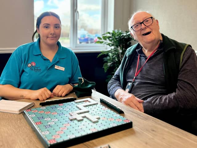 Rebecca Major, Activities Co-ordinator, with Meadowcroft resident Michael laughing together and playing Scrabble.