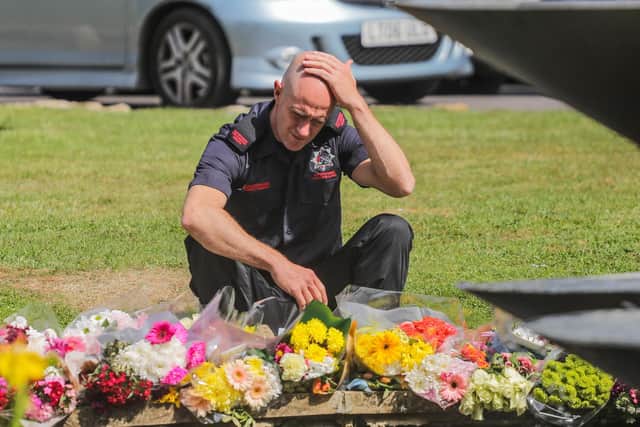 A firefighter grieves for his colleagues at the floral memorial in Garth Park