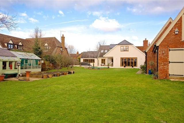 The rear garden is lawned with mature trees including willow, apple and pear, established shrubs, and a pond