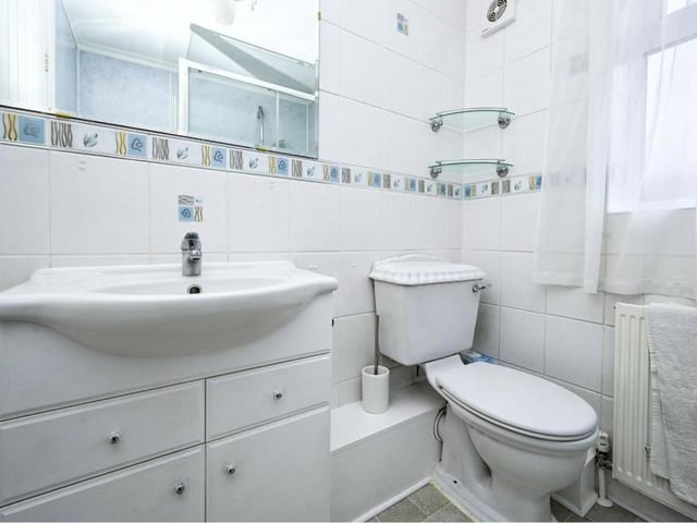 The neat and well-presented shower room sits across the hall from the master bedroom. This photo shows the wash hand basin and vanity unit, large mirror and low-flush WC.