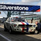A member of the pit crew checks the tyre pressure of a 1965 Ford Mustang during the HSCC Thundersports qualification stage of the Silverstone Festival. Photo: Getty Images.