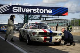 A member of the pit crew checks the tyre pressure of a 1965 Ford Mustang during the HSCC Thundersports qualification stage of the Silverstone Festival. Photo: Getty Images.