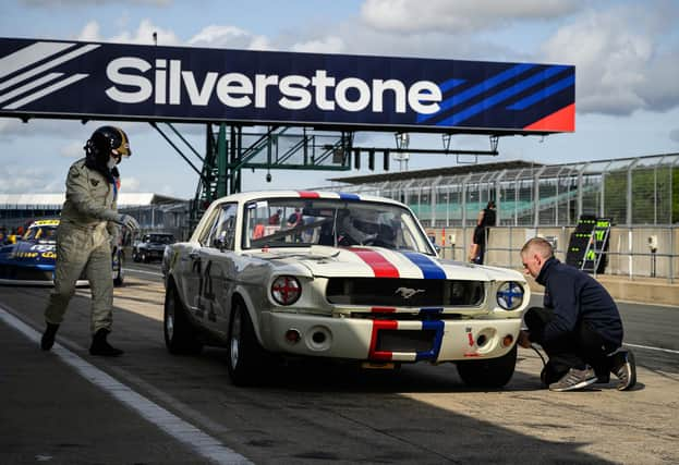 A member of the pit crew checks the tyre pressure of a 1965 Ford Mustang during the HSCC Thundersports qualification stage of the Silverstone Festival. Photo: Getty Images.