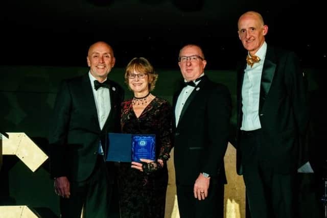 Penny Mason with her award, presented by ek robotics managing director, Chris Price (centre), along with the Royal Latin's chair of governors, Phil Dart (left) and headteacher, David Hudson (right)