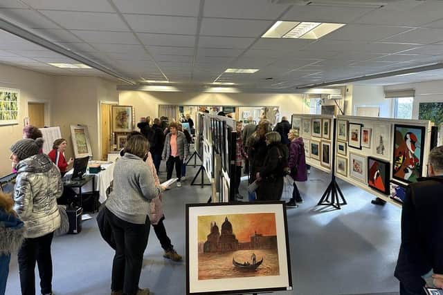 The downstairs hall of the Pop-Up Art Weekend with art enthusiasts appreciating the art on display.