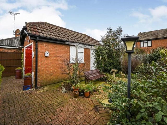 The detached garage at the side of the £210,000-plus bungalow, and a glimpse of the back garden with its pleasant seating area.