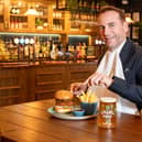 Royal butler eating a burger with a knife and fork