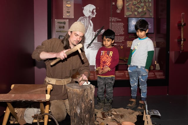Neel (six) and Brij (four) watch a Bronze Age re-enactor at work