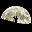 A person holding a witch's hat watches the Blue Moon rise over Castle Hill in Huddersfield, it will be the last full moon to fall on Halloween until 2039. (photo from PA Archive/PA Images)