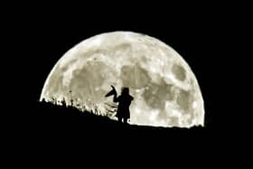 A person holding a witch's hat watches the Blue Moon rise over Castle Hill in Huddersfield, it will be the last full moon to fall on Halloween until 2039. (photo from PA Archive/PA Images)