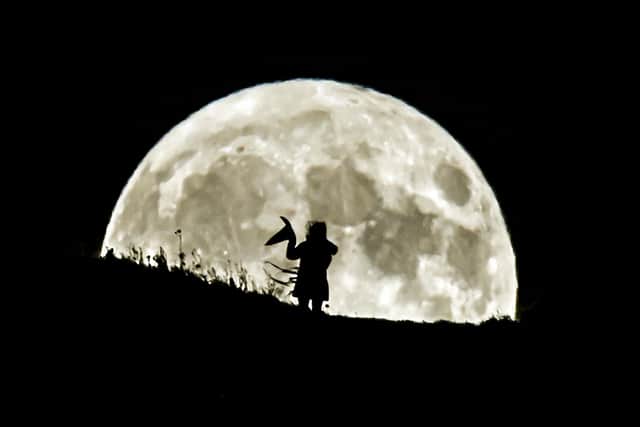A person holding a witch's hat watches the Blue Moon rise over Castle Hill in Huddersfield, it will be the last full moon to fall on Halloween until 2039. (photo from PA Archive/PA Images)