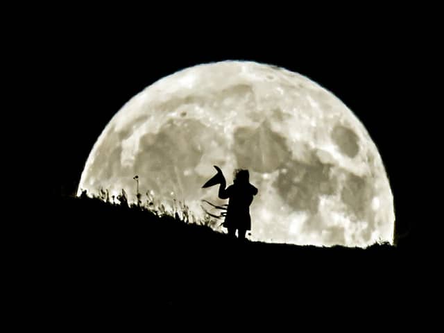 A person holding a witch's hat watches the Blue Moon rise over Castle Hill in Huddersfield, it will be the last full moon to fall on Halloween until 2039. (photo from PA Archive/PA Images)