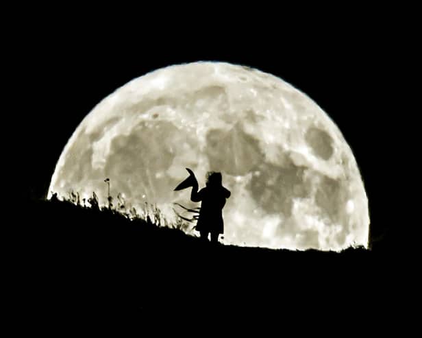 A person holding a witch's hat watches the Blue Moon rise over Castle Hill in Huddersfield, it will be the last full moon to fall on Halloween until 2039. (photo from PA Archive/PA Images)