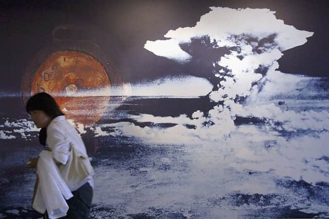 A visitor passes by a wall displaying a picture of the mushroom cloud pictured when the atomic bomb was dropped on Hiroshima (Photo: Junko Kimura/Getty Images)