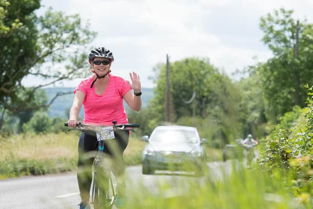 A rider waves for the camera as she cycles through the Buckinghamshire countryside