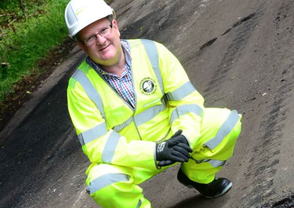 Cllr Mark Shaw pictured next to a pothole