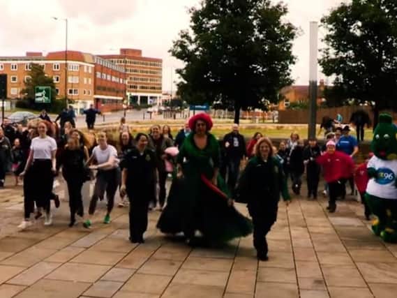 A still from the video showing La Voix and members of community groups outside the Waterside Theatre