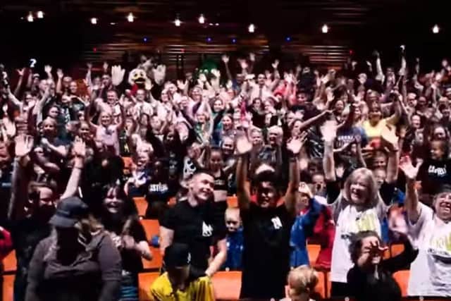 A still from the video showing members of community groups inside the theatre dancing along to a performance of the panto song This is Smee
