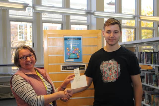 Alex Burridge (right) receives his prize from the library service's Hazel Edwards