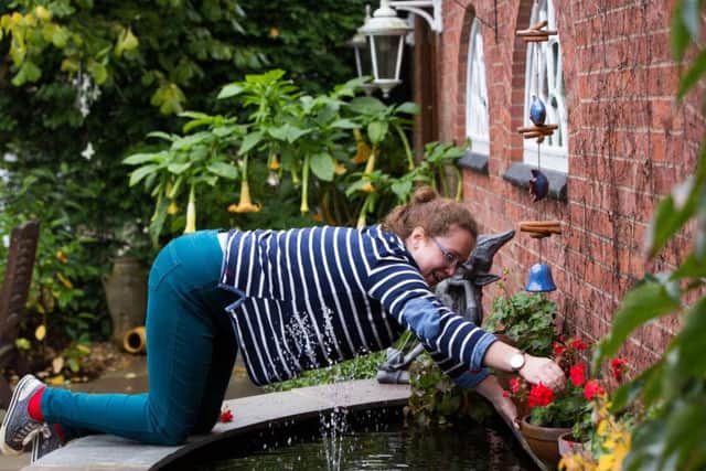 Garden designer Lucie Ponsford in action as she stretches over a water feature to tend to some plants