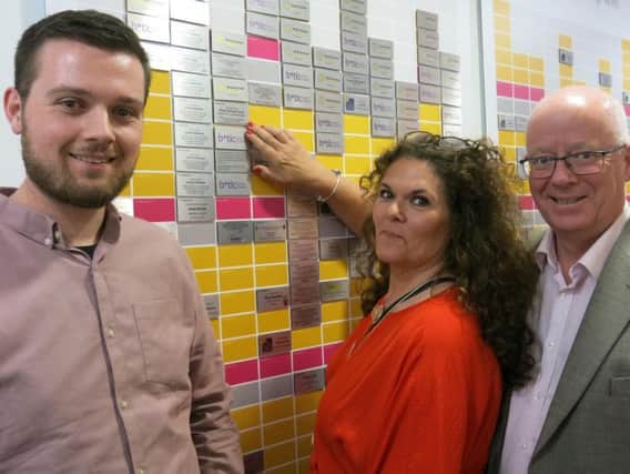 Ben, Sarah and David Long pictured next to Brain Tumour Research's wall of hope