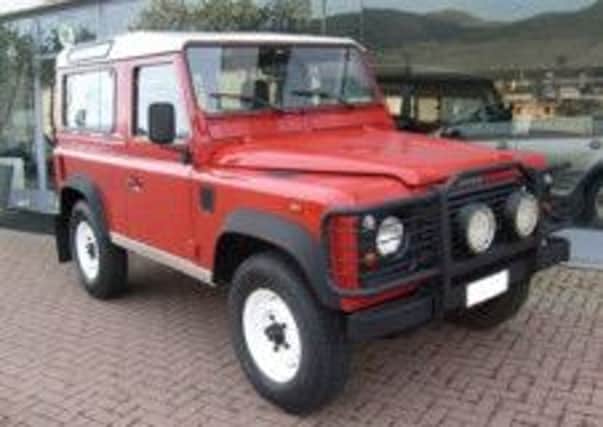 A red Land Rover Defender 100, similar to the Laines' car