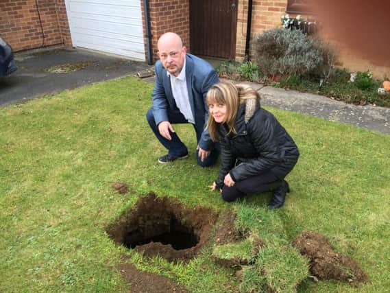 Kynaston Avenue Stoke Mandeville. Emma James and councillor Marcus Rogers peer into a deep hole, with steps, which has appeared in Emma's garden