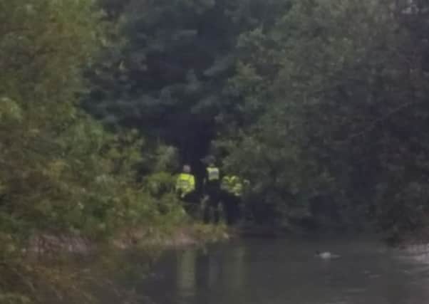 Police gather by woodland next to the lake on Watermead